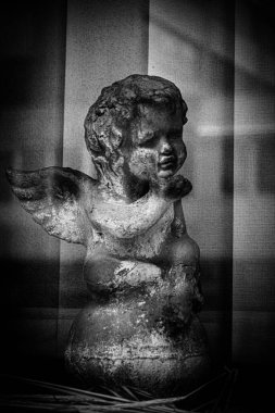 Pejmürde bir turuncu melek heykeli. Vitrinde bir yansıma var. Balonun üzerinde oturuyor..