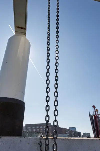 İki metal zincire karşı soğuk kuzey gökyüzünde bir uçak yolu var. Arka planda bir apartman ve yükseltilmiş bir köprü var. Fotoğraf deniz kafesinde çekildi..