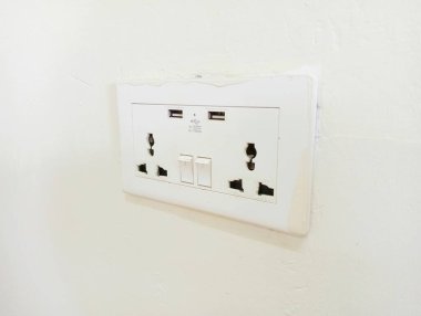 Fişi ve siyah duvarı olan beyaz elektrik prizi