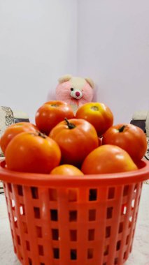 Oyuncak ayı domatesli bir tabağın önünde oturuyor. Taze domates sebzeler, çiftlik organik vektörü. Doğa arka planında sepetteki olgun domatesler..