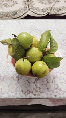 Cam Masa 'da taze guava meyvesi izole edilmiş. Sepette taze guava meyveleri, pembe arka planda izole edilmiş..