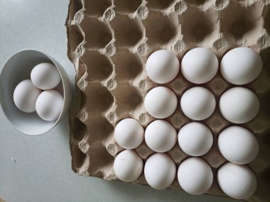 Karton tepside beyaz yumurta ve tabakta yumurta..