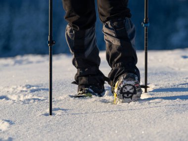Close up of a man hiking on a mountain covered on snow, in boots with shoe skpikes. Outdoor winter trekking