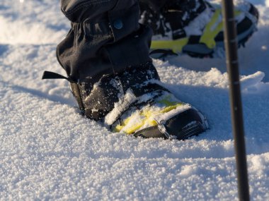 Close up of a man hiking on a mountain covered on snow, in boots with shoe skpikes. Outdoor winter trekking