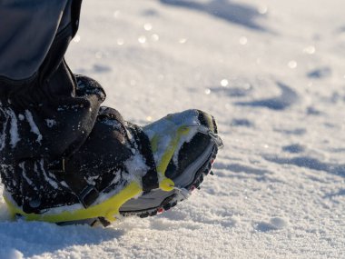 Close up of a man hiking on a mountain covered on snow, in boots with shoe skpikes. Outdoor winter trekking