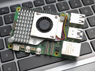 Galati, ROMANIA - 10 Kasım 2023: Aktif soğutuculu bir Raspberry Pi 5 'in klavyede yakın çekimi. Ahududu Pi, İngiltere 'de geliştirilmiş kredi kartı büyüklüğünde tek kartlı bir bilgisayardır.
