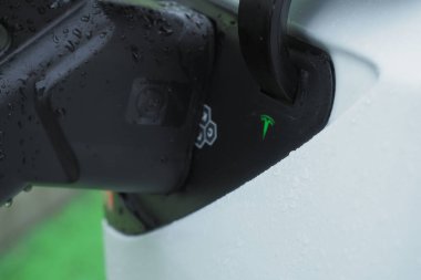 Galati, Romanya - 26 Aralık 2024: Tesla limanı yağmurlu bir günde hızlı şarj istasyonuna bağlandı