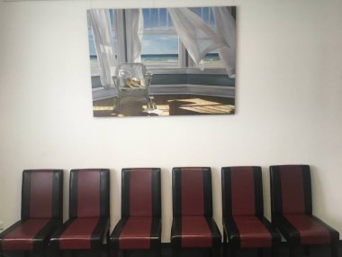 Bekleme odasında, beyaz arka planda yan yana sandalyeler.