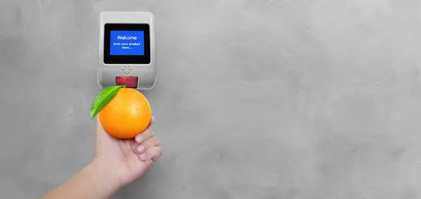 Price scanner with oranges in hand isolated on cement background