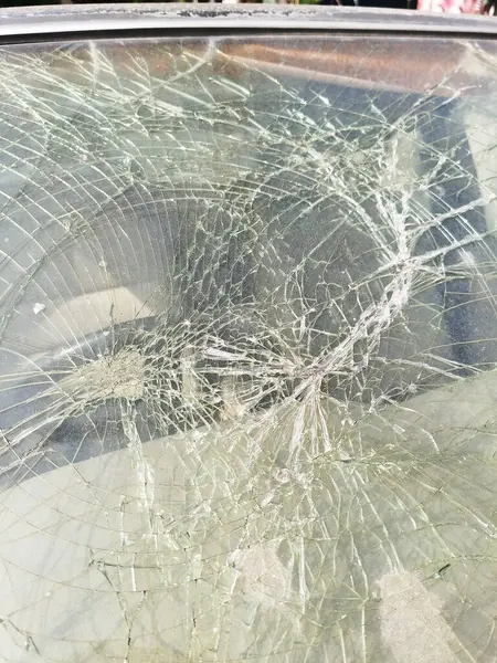 Broken windshield on car. Traffic accident with crash glass on vehicle. Strong impact on automobile. Car damaged consequences after heavy storm.