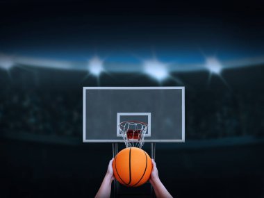 Basket sepetine basket topu atmak üzere olan bir el ile arka planda bir amfi tiyatro var..