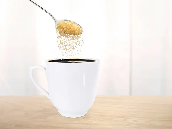 Spoon pour sugar into a coffee mug on the wooden floor inside the room.