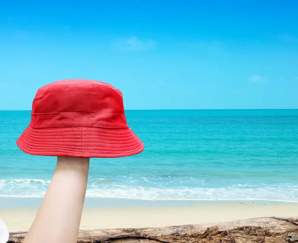 red bucket hat in hand with beach background