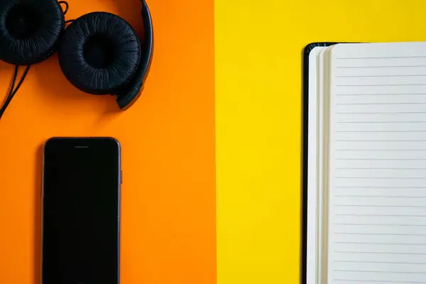headphone and notebook on an orange background, flat lay image