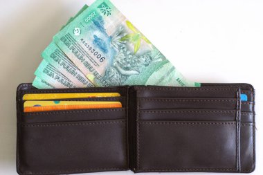 Üzerinde banka kartı ve Endonezya rupiası banknotları olan deri cüzdan beyaz arka planda izole edilmiş 20 bin rupiah.