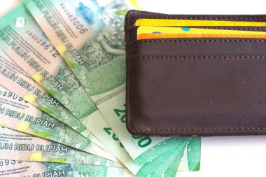 Üzerinde banka kartı ve Endonezya rupiası banknotları olan deri cüzdan beyaz arka planda izole edilmiş 20 bin rupiah.