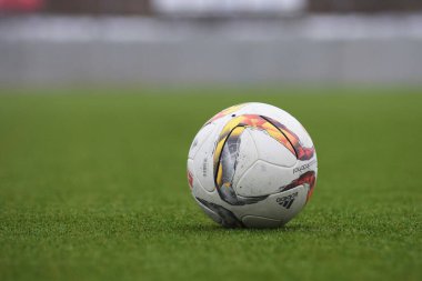 Çimlerde ve stadyumda futbol. Futbol stadyumunun arka planında çimlerin üzerinde yakın plan futbol topu..