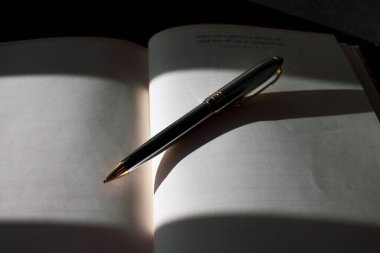 Bir kalem ve gölgeli bir defter. Dolma kalem ve defter. Gölgede hikaye yazma.