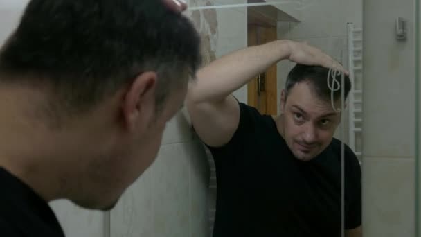 鏡の前にいるブルネットの男は髪を磨かないと怒る 鏡の前にいる男は 髪をスタイルすることができないと神経質になる — ストック動画