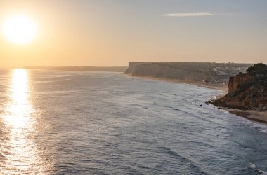Okyanusta gün batımının sakin manzarası. Güneş ışığı suya yansıyor. Lagos, Portekiz 10 Ekim 2023.