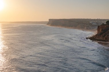 Okyanusta gün batımının sakin manzarası. Güneş ışığı suya yansıyor. Lagos, Portekiz 10 Ekim 2023.