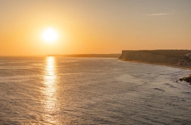 Okyanusta gün batımının sakin manzarası. Güneş ışığı suya yansıyor. Lagos, Portekiz 10 Ekim 2023.