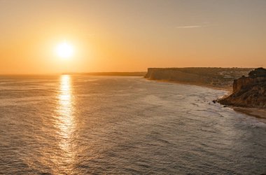 Okyanusta gün batımının sakin manzarası. Güneş ışığı suya yansıyor. Lagos, Portekiz 10 Ekim 2023.