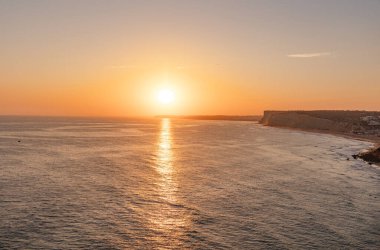 Okyanusta gün batımının sakin manzarası. Güneş ışığı suya yansıyor. Lagos, Portekiz 10 Ekim 2023.