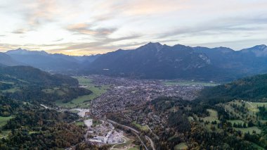 Dağlardan ve Bavyera dağlarının eteklerinden manzarayı seyret. Bir sonbahar akşamında orman ve dağlar. Mavi gökyüzü ve bulutlar.