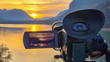 Günbatımını kaydeden video, Sylvensteinsee 'de üç ayaklı kamera sonbaharda Alp eteklerinde gölün sahilinde..