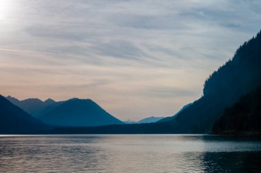 Bir sonbahar akşamında Alplerin eteklerinin güzel manzarası. Su ve sarı-kırmızı ağaçlar