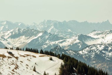 Sabah sisinde ufukta, Wallberg Dağları 'ndan Alp eteklerinin manzarası var. Ufuktaki dağ silsilesi sabah sisinde.