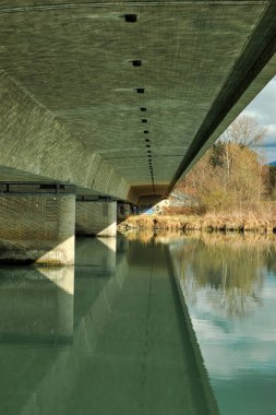 Baharda Bavyera 'da, Inn Nehri üzerindeki yol köprüsünün altından manzara. Yeşil su, gri beton.