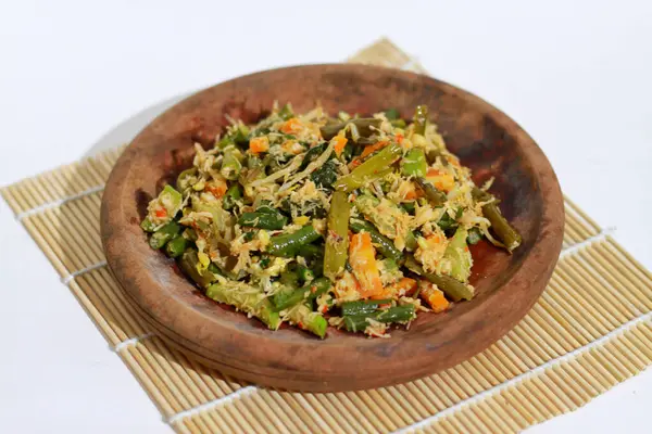 Urap Sayur Endonezya 'nın geleneksel yemeğidir. Baharatlı ve baharatlı çeşitli sebzelerle karıştırılmış bir salata tabağı. Beyaz arka planda izole edilmiş..