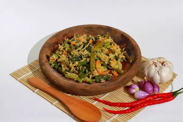 Urap Sayur Endonezya 'nın geleneksel yemeğidir. Baharatlı ve baharatlı çeşitli sebzelerle karıştırılmış bir salata tabağı. Beyaz arka planda izole edilmiş..