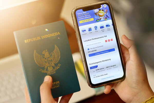 Cropped hand of woman shopping online for flight tickets on airline website with smartphone.tiket.com mobile application.