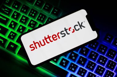 Endonezya-Nisan, 23. 2024: Ekranda ABD stok fotoğrafçılık şirketi Shutterstock Inc. 'in logosunun bulunduğu cep telefonu. Arkaplanda bilgisayar klavyesi