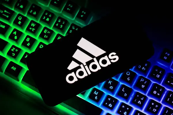 Adidas logosu akıllı telefon ekranında gösterilen bir Alman ayakkabı şirketi logosudur. Endonezya-23 Nisan 2024. Arkaplanda bilgisayar klavyesi