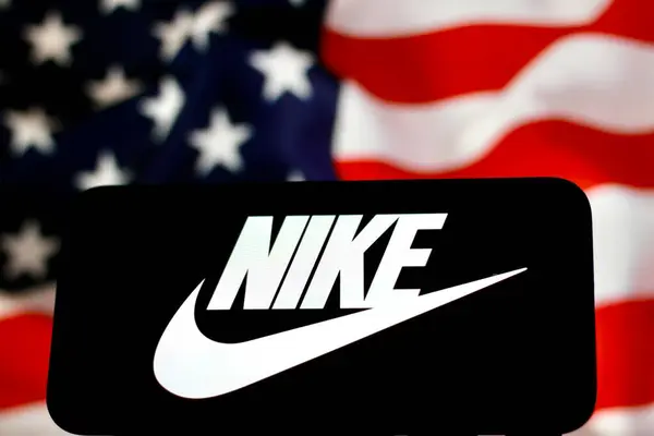 Nike Logo, ABD 'li bir spor ekipmanı tedarikçisi. Akıllı telefon ekranında gösteriliyor. Endonezya-23 Nisan 2024. ABD bayrak arka planı 