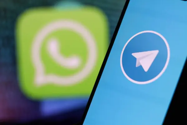 Arkaplanda WhatsApp logosu olan akıllı telefon ekranındaki Telegram logosu. Endonezya - 28 Nisan 2024.