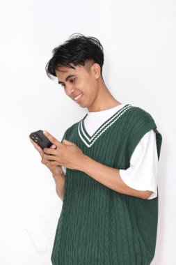 Beyaz arka planda akıllı telefonlu Asyalı bir gencin stüdyo çekimi.