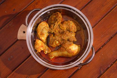 Ayam bumbu kuning or chiken curry served in bowl on woodle table.