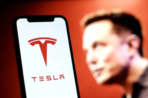 Bu fotoğrafta Tesla logosu arka planda CEO Elon Musk ile akıllı telefon ekranında gösteriliyor.