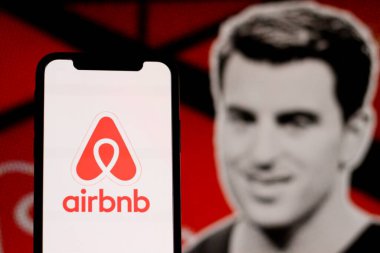 Bu resimde Airbnb logosu arka planda CEO Brian Chesky ile birlikte akıllı bir telefonda sergileniyor. Endonezya - 25 Mayıs 2024.
