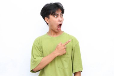 Yeşil gömlekli genç adam beyaz bir arka planı işaret ediyor. Şok olmuş bir yüz ifadesini vurgular