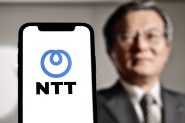 Indonesia - JUNE, 6TH, 2024: In this photo The NTT logo is displayed on a smartphone screen with CEO Akira Shimada in background clipart