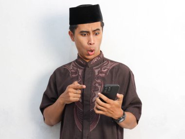 Beyaz arka planda izole edilmiş akıllı telefonlu Asyalı Müslüman adamın mutlu yüzünün portresi. Ramazan kavramı.