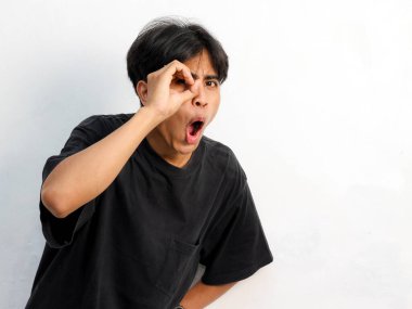 Siyah tişört giyen Asyalı genç bir adamın beyaz arka planda elleri izole dürbün yapan komik yüzünün portresi..