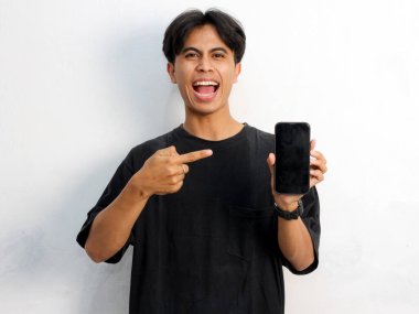 Siyah tişörtlü, cep telefonu tutan Asyalı bir adamın beyaz arka planda izole edilmiş komik bir portresi.