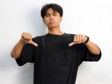 Beyaz arka planda izole edilmiş bir reklam için siyah tişört giyen Asyalı genç bir adamın portresi boş yeri işaret ediyor..